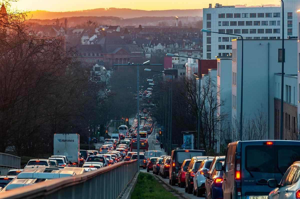Flux dense de véhicules sur une route urbaine entourée de bâtiments, au coucher du soleil