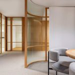 Intérieur moderne avec table ronde, chaises, cloisons en verre courbes
