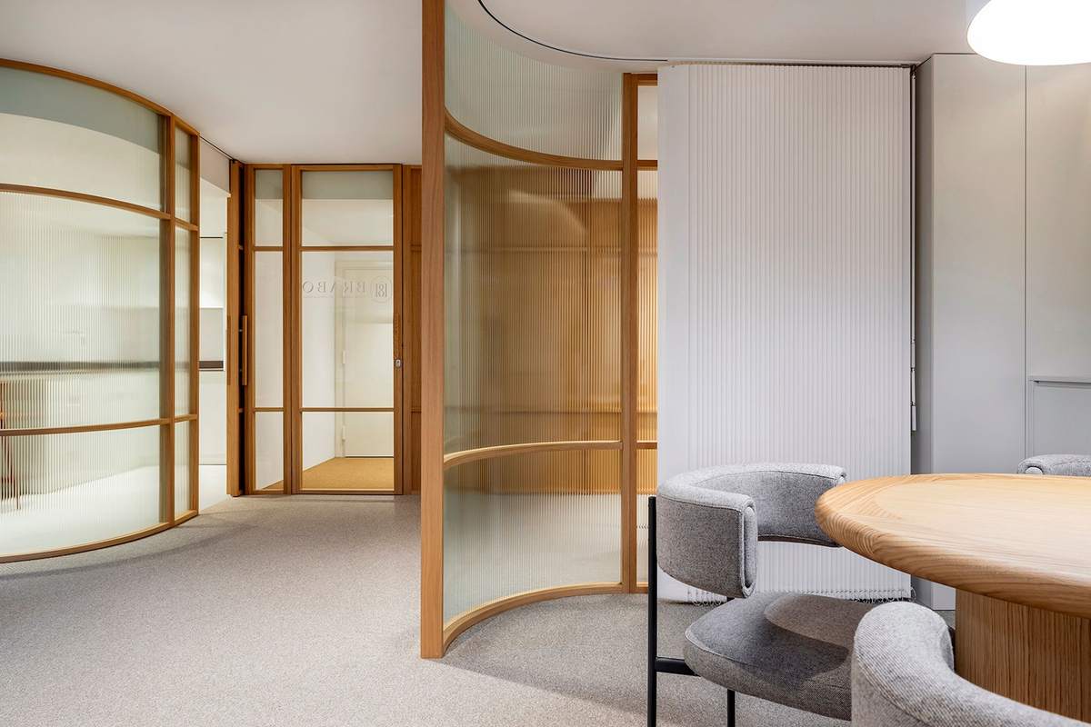 Intérieur moderne avec table ronde, chaises, cloisons en verre courbes