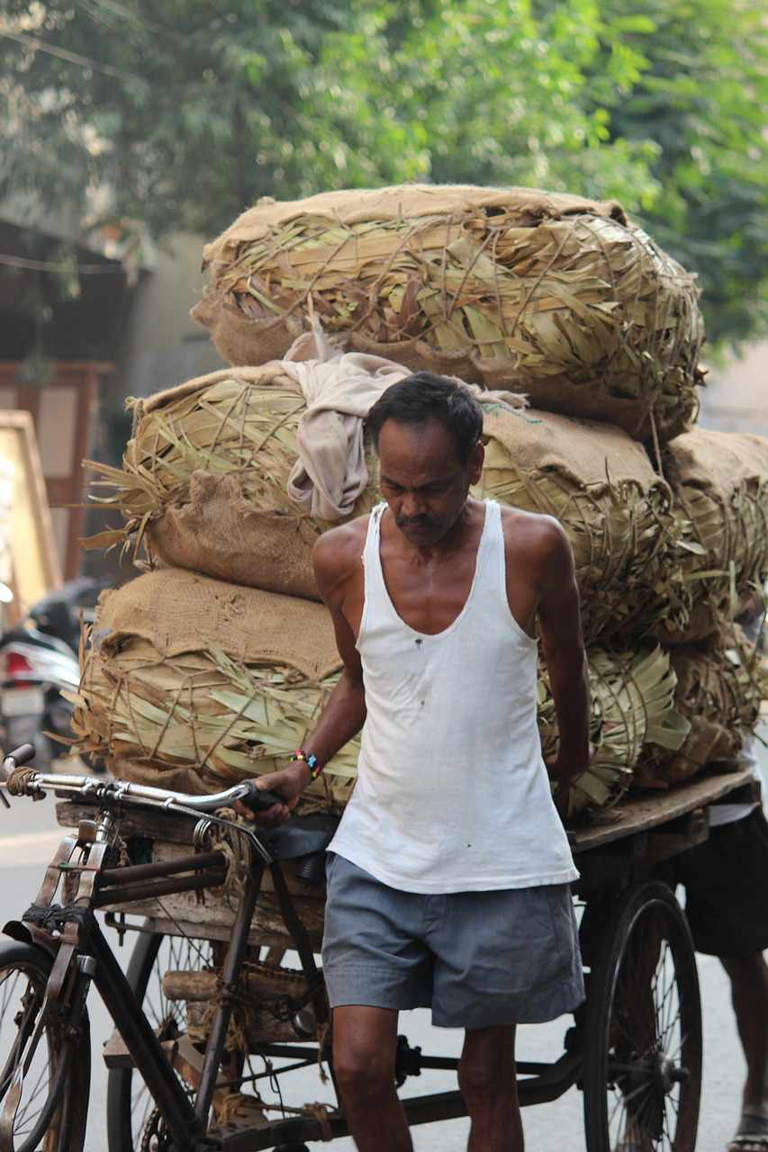 Un homme pousse une bicyclette surchargée de sacs sur une rue