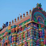 Tour colorée d'un temple hindou orné de sculptures sous ciel bleu