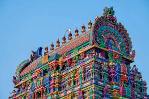 Tour colorée d'un temple hindou orné de sculptures sous ciel bleu