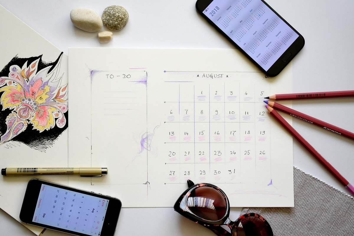 Planification d'août sur papier avec smartphone, crayons et accessoires