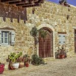 Maison de pierre avec porte et fenêtres, pots de plantes sur le sol