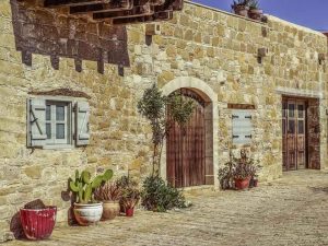 Maison de pierre avec porte et fenêtres, pots de plantes sur le sol