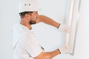 un ouvrier installe un panneau blanc sur un mur
