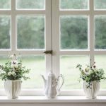 Deux vases de fleurs et une théière blanche sur le rebord d'une fenêtre