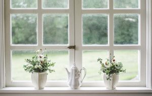 Deux vases de fleurs et une théière blanche sur le rebord d'une fenêtre