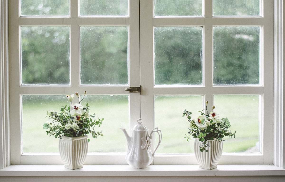 Deux vases de fleurs et une théière blanche sur le rebord d'une fenêtre